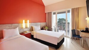 A hotel room with two beds, a desk, a chair, a TV, and a balcony with a view. - Primera Hotel Seminyak (Seminyak)