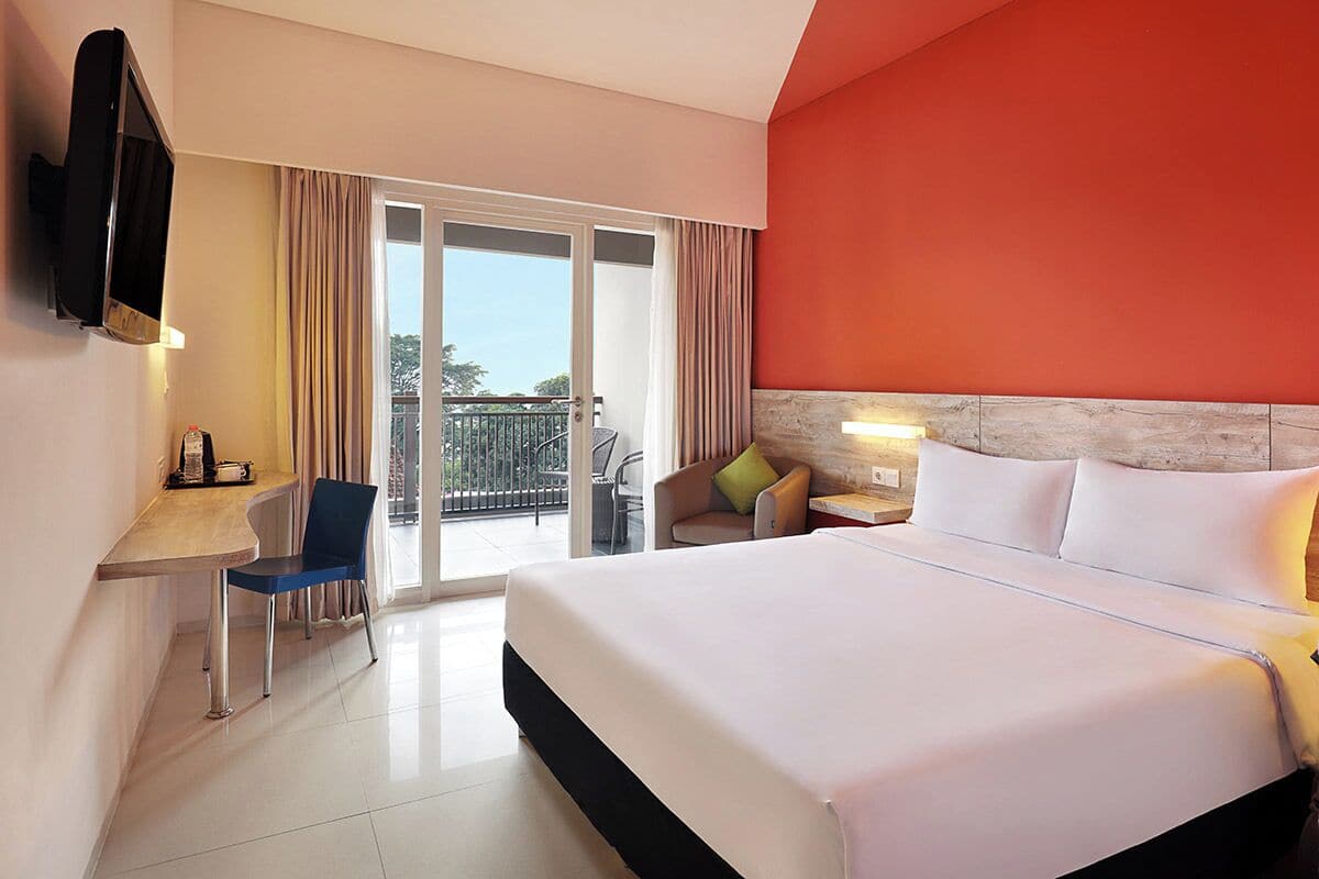 Une chambre d’hôtel avec un lit, un bureau, une chaise, une télévision et un balcon.