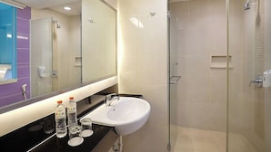 A modern bathroom with a glass shower enclosure, a white sink, and a mirror above the sink. - Primera Hotel Seminyak (Seminyak)