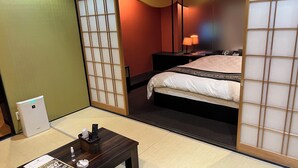 Een hotelkamer met een bed, een bureau met een lamp en een schuifdeur van shoji-papier.