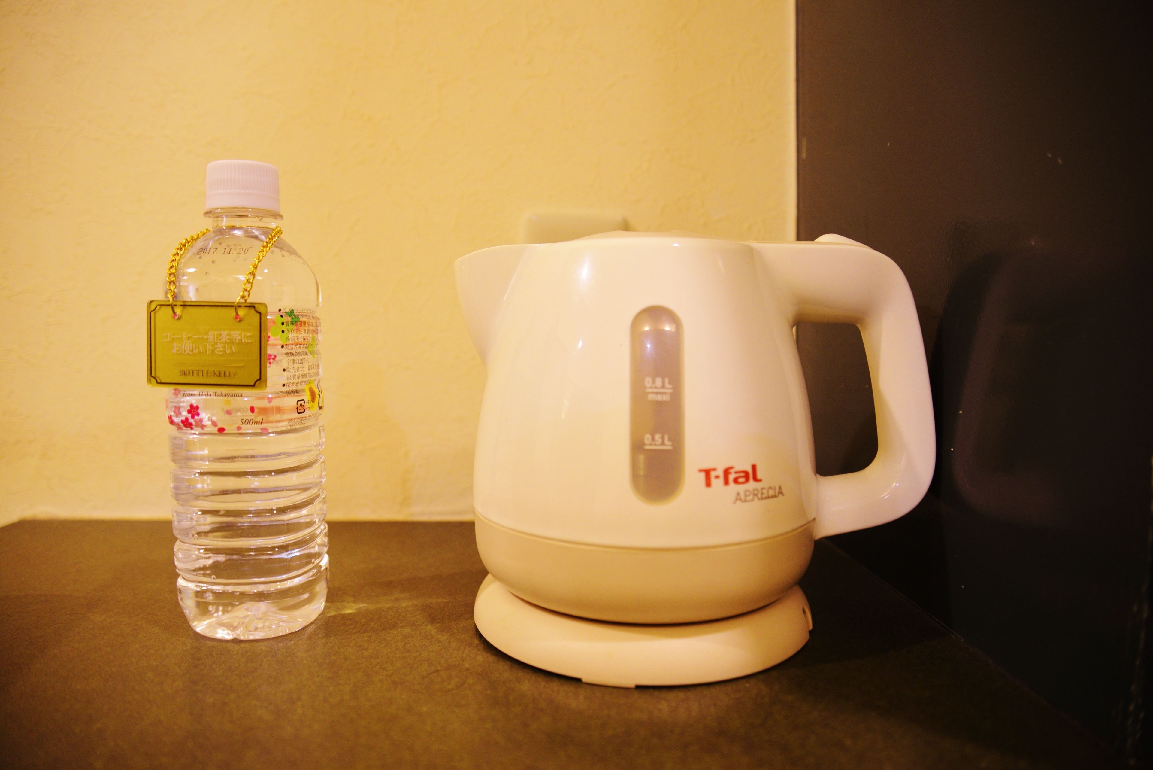 A bottle of water and a white electric kettle on a countertop.