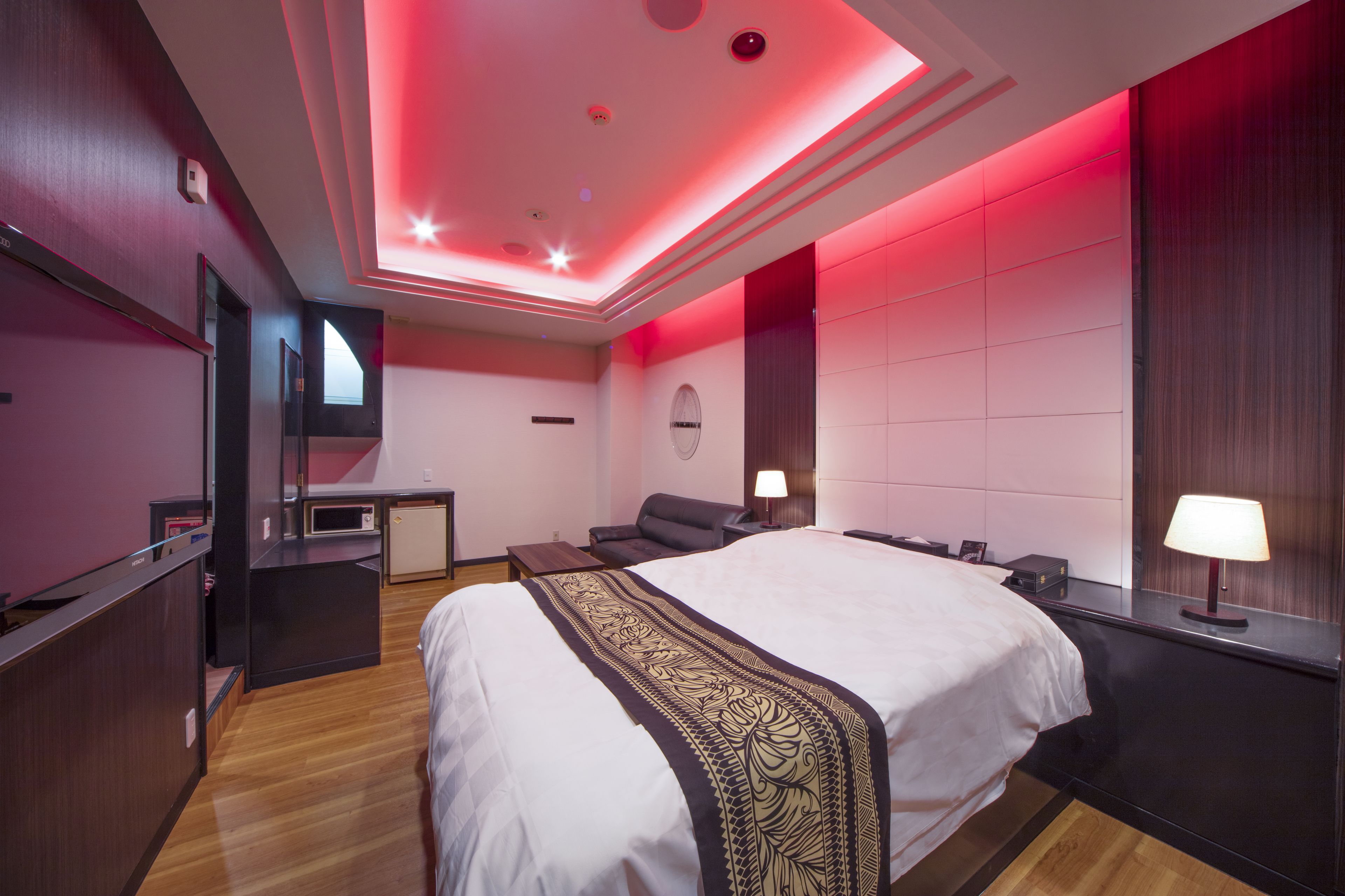 A modern hotel room with a large bed, a desk, and a seating area.