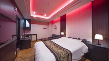 A modern hotel room with a large bed, a desk, and a seating area.
