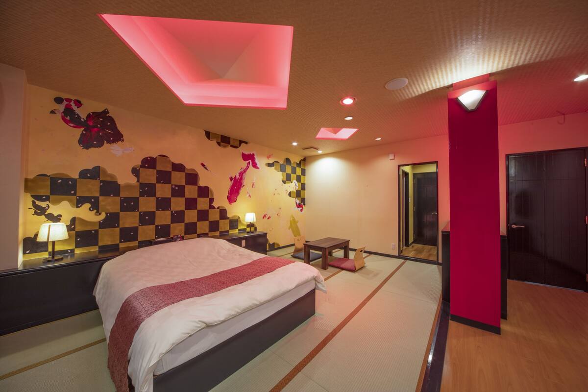 Ein Hotelzimmer mit einem großen Bett, einem kleinen Tisch, einem Stuhl und einem Spiegel.