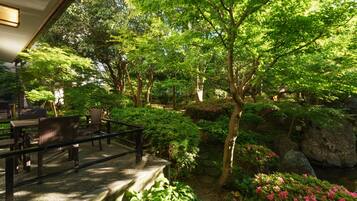 A serene garden with a wooden deck, stone pathway, and lush greenery.