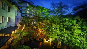 A traditional Japanese-style garden with a koi pond, surrounded by lush greenery and illuminated by soft lighting. - Hotel Hoho "A hotel overlooking the Echigo Plain and the Yahiko mountain range" (Niigata)