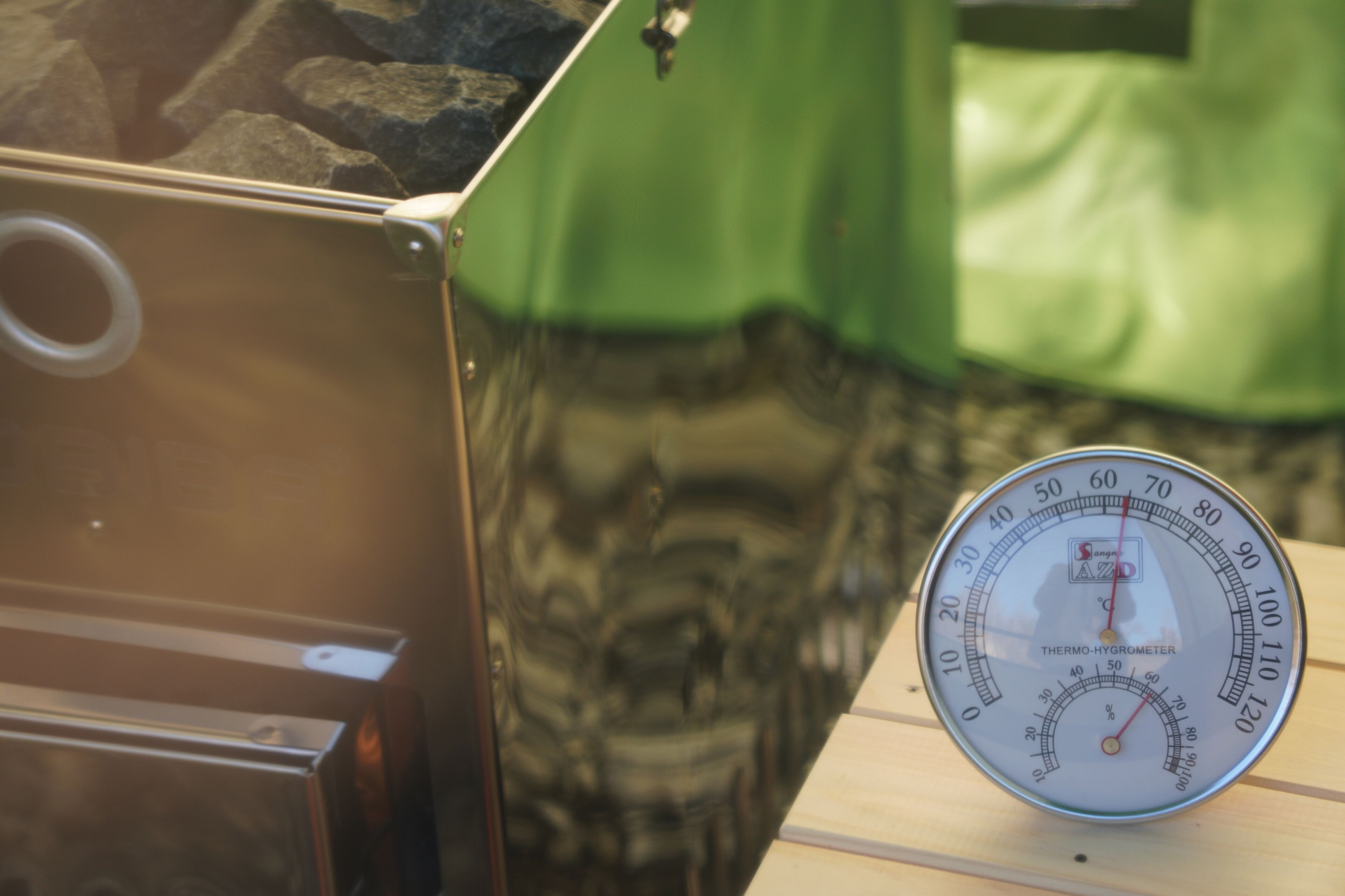 A thermometer and a metallic object with a circular opening on a wooden surface.