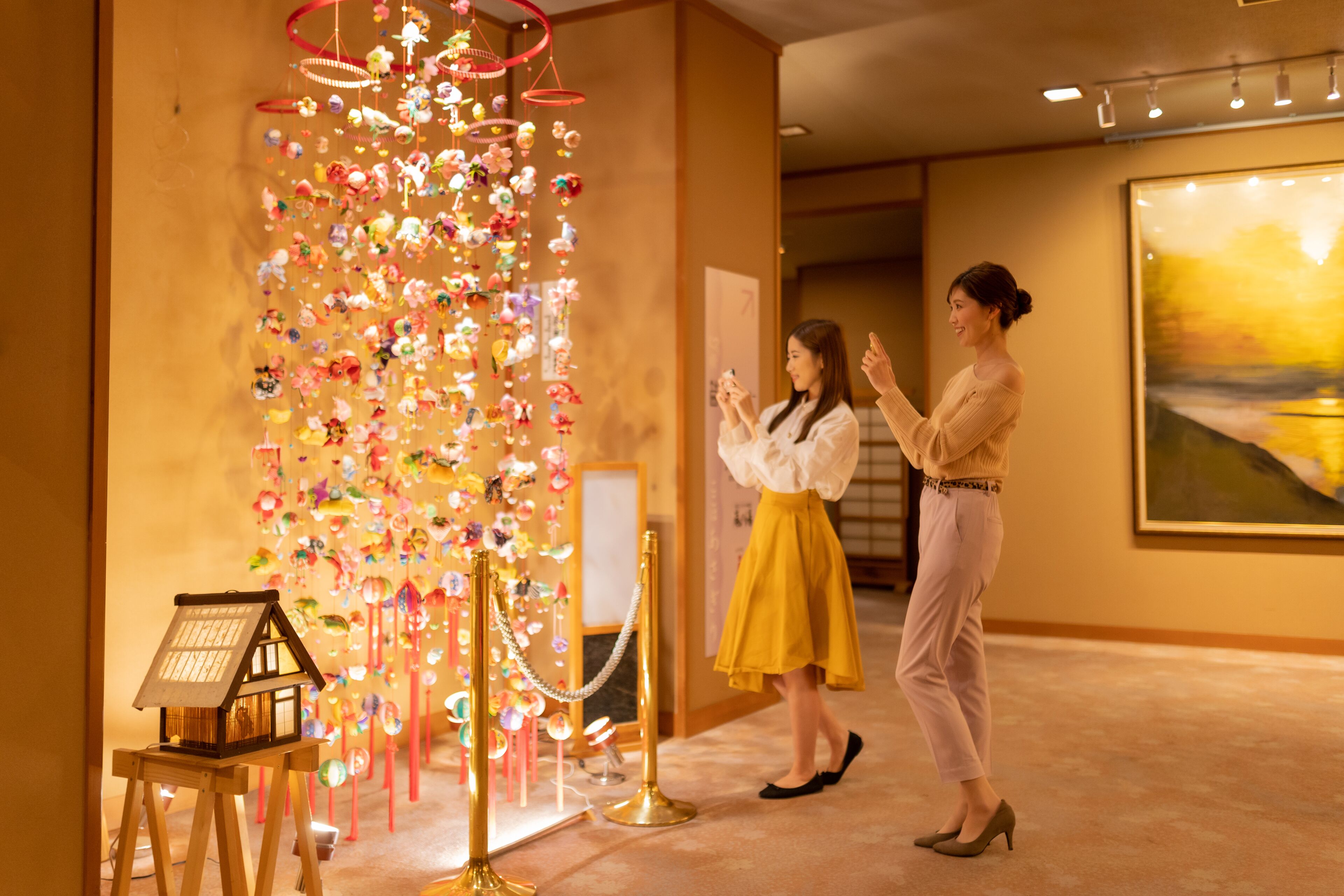 An art gallery with a large, colorful installation hanging from the ceiling.