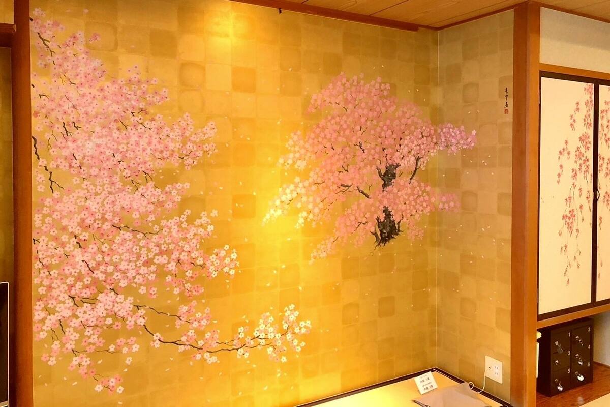 A room with a traditional Japanese-style wall featuring cherry blossom paintings.