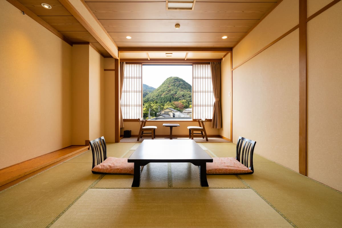 A traditional Japanese room with tatami flooring, a low table, and chairs.