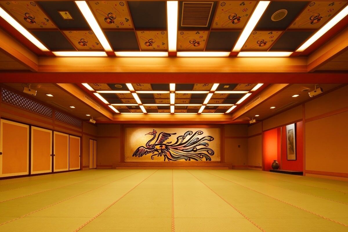 Een kamer met tatami matten, een groot muurschildering, houten schuifdeuren en ingebouwde verlichting.