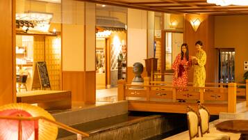 A traditional Japanese interior with a wooden bridge, tatami mats, and a reception area.