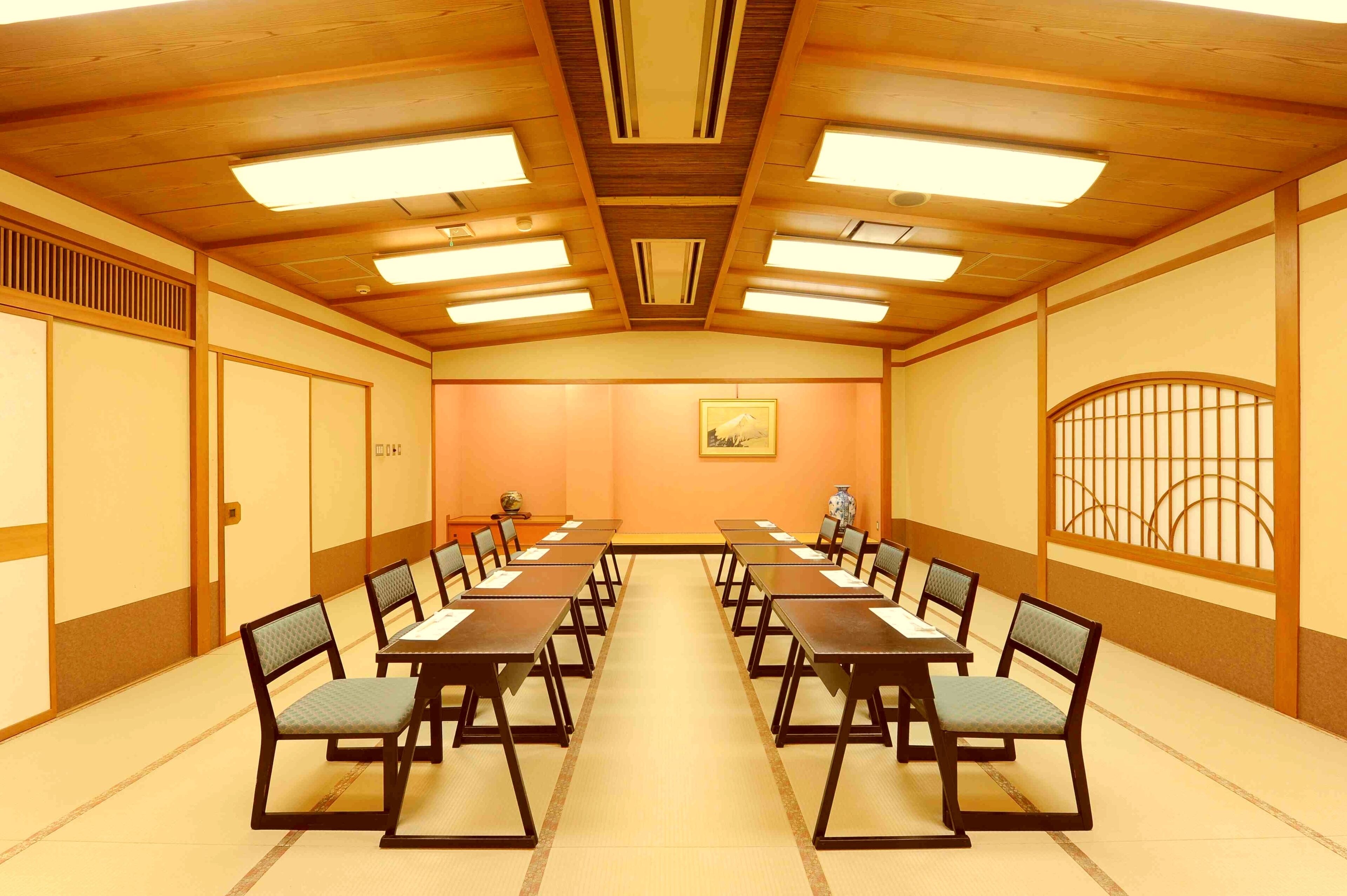 Un salón de conferencias con paneles de madera, una mesa central y sillas dispuestas alrededor.