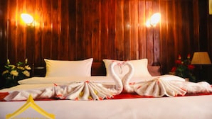 A hotel room with wooden paneling, a bed with white linens, and a decorative swan towel arrangement. - Phonepraseuth Guesthouse (Luang Prabang)