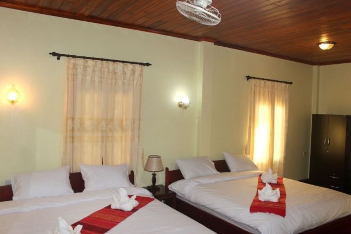 A hotel room with two beds, a ceiling fan, wall-mounted lamps, and curtains.