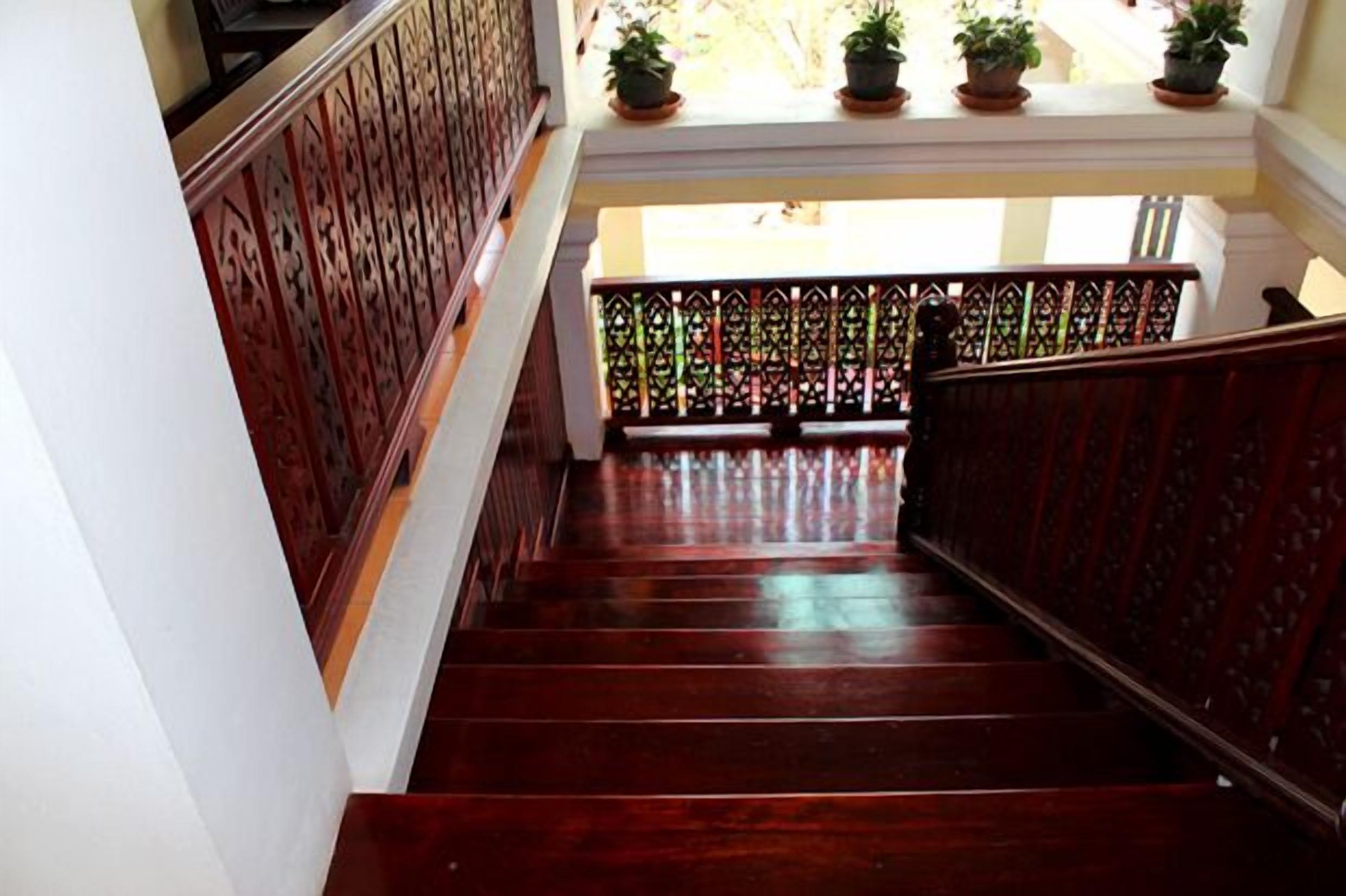 A wooden staircase with ornate railings and potted plants at the top.