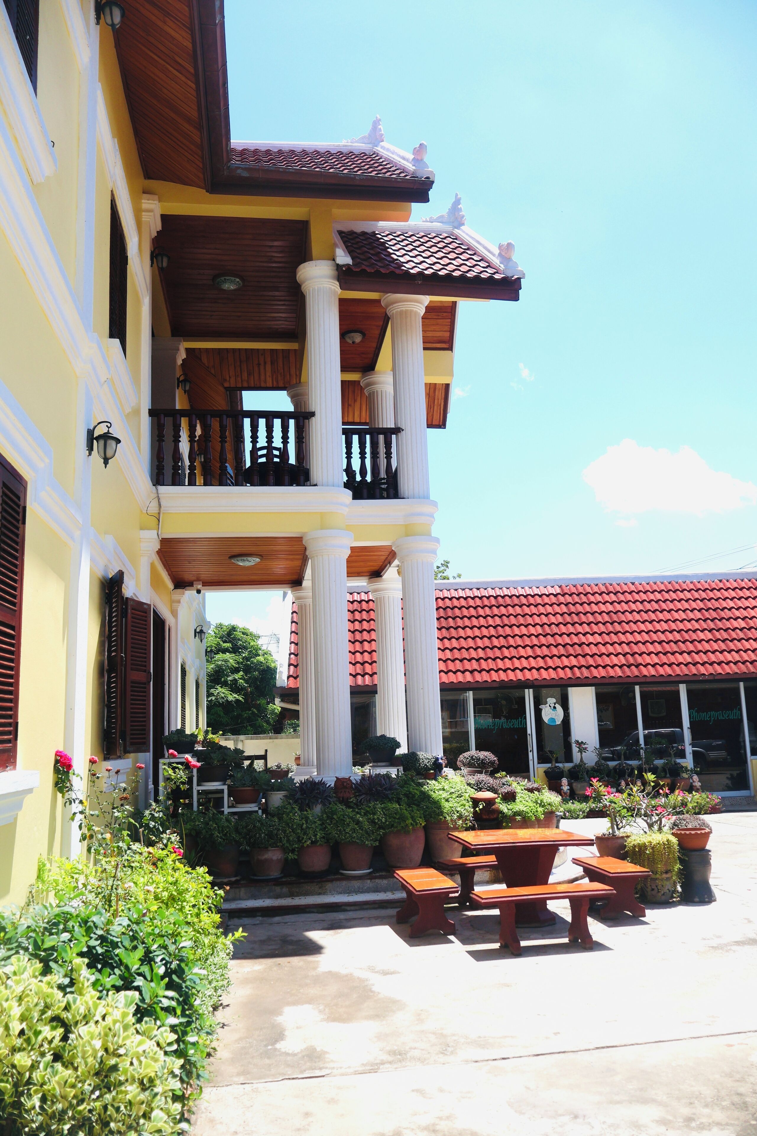 A building with a balcony, columns, and potted plants.
