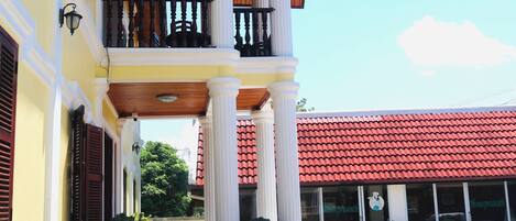 A building with a balcony, columns, and potted plants.