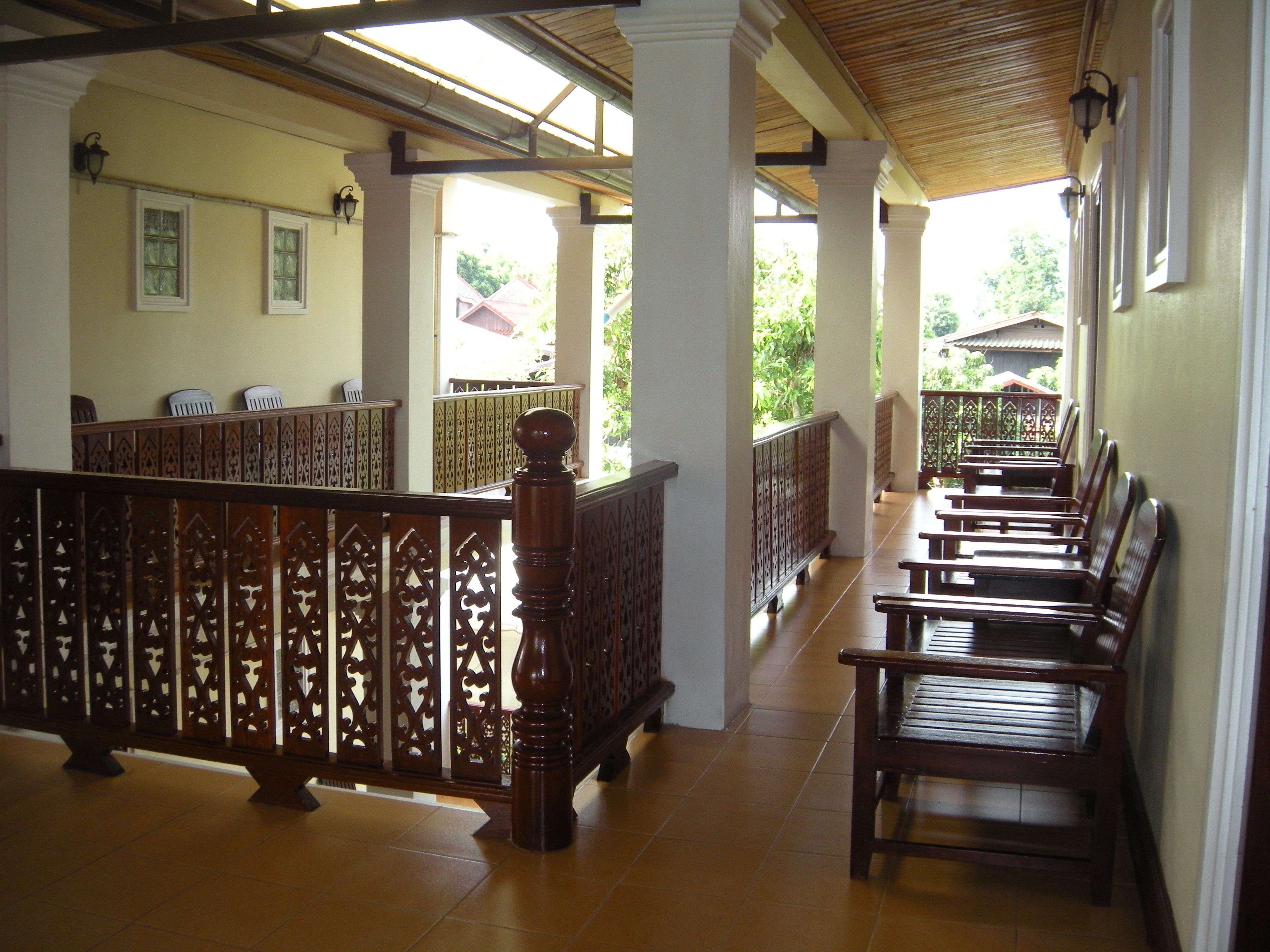 A covered corridor with wooden benches and a decorative railing.