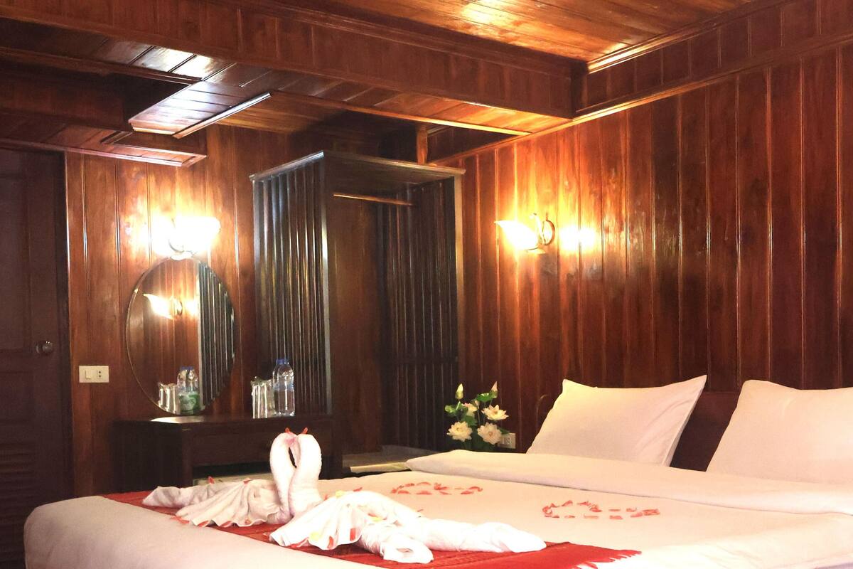 Ein Hotelzimmer mit Holzwandverkleidung, einem Bett mit weißer Bettwäsche, einem Spiegel und zwei Wandleuchten.