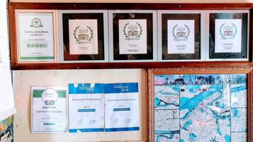Framed awards and certificates on a wall, including TripAdvisor and HolidayCheck recognitions, and a framed map.