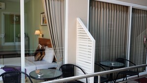 A balcony with a glass railing, a sofa, and a table with chairs. - Chilli Hotel & Restaurant (Rayong)