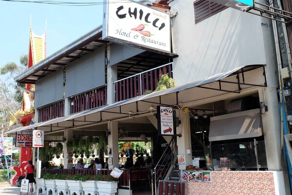 A two-story building with a sign for 'Chilli Hotel & Restaurant' on the upper floor.