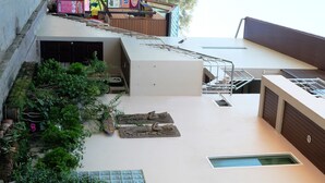 A modern building with a flat roof, a garage, and a small garden area with plants and a decorative stone feature. - Chilli Hotel & Restaurant (Rayong)
