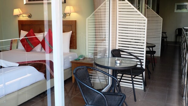 A hotel room with a bed, a nightstand, a table with chairs, and a staircase. - Chilli Hotel & Restaurant (Rayong)