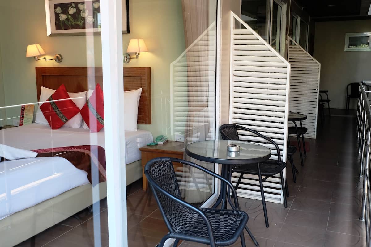 A hotel room with a bed, a nightstand, a table with chairs, and a staircase.