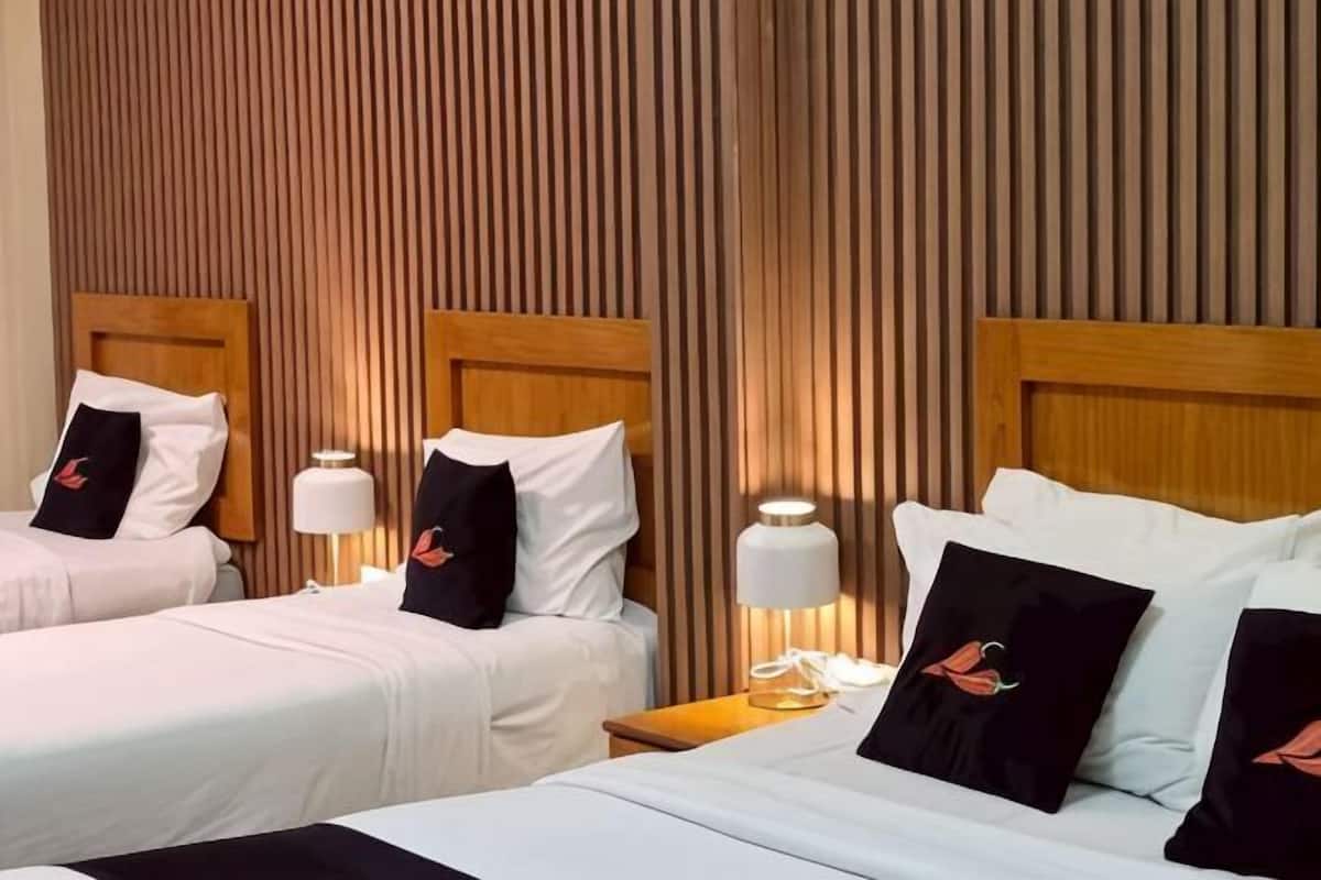 A hotel room with two beds, wooden headboards, white bedding, and bedside lamps.