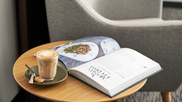 Una mesa con un libro, una taza de café y una galleta.