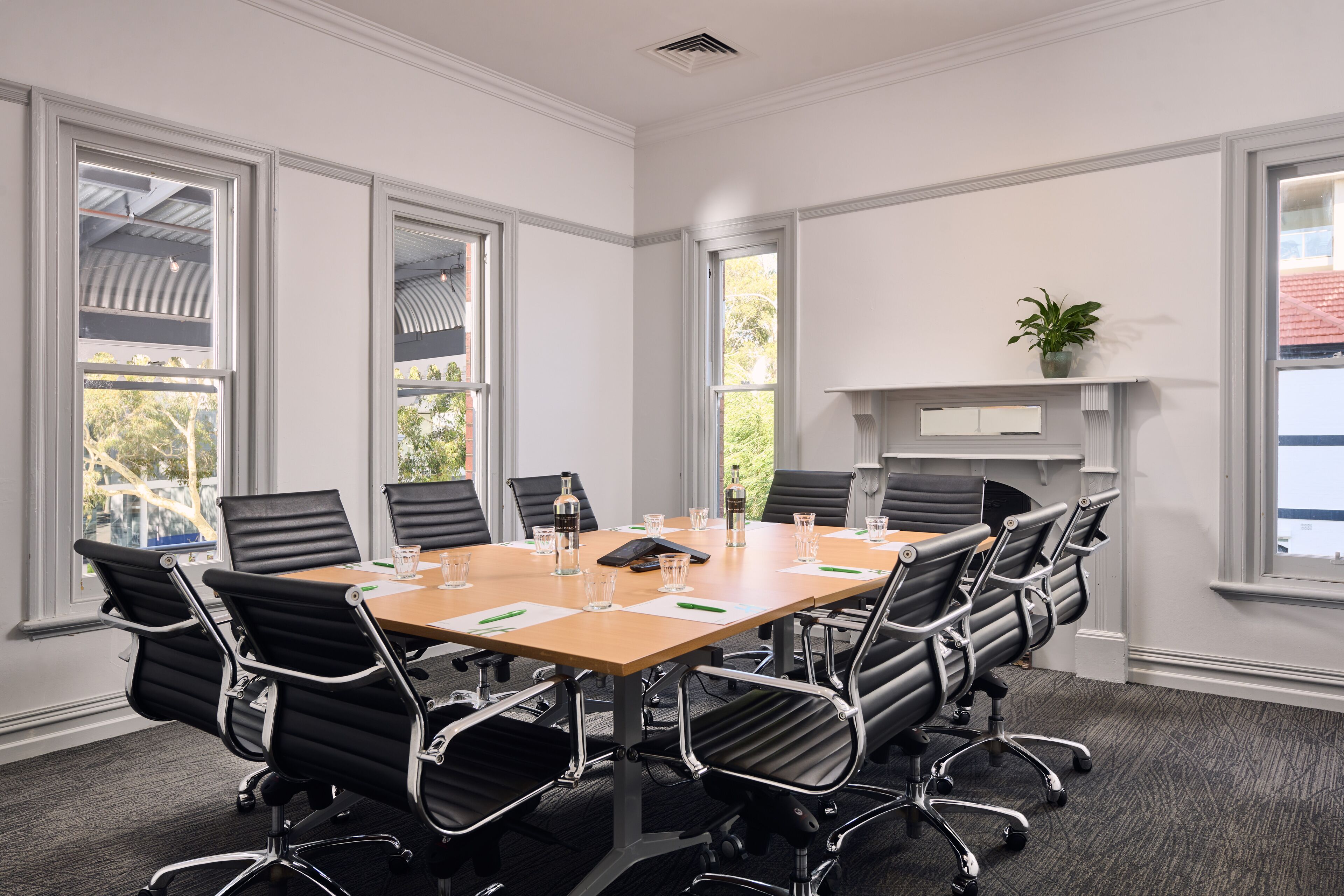 A conference room with a large table, black chairs, and a fireplace.
