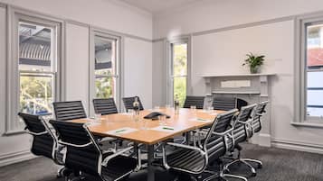A conference room with a large table, black chairs, and a fireplace.