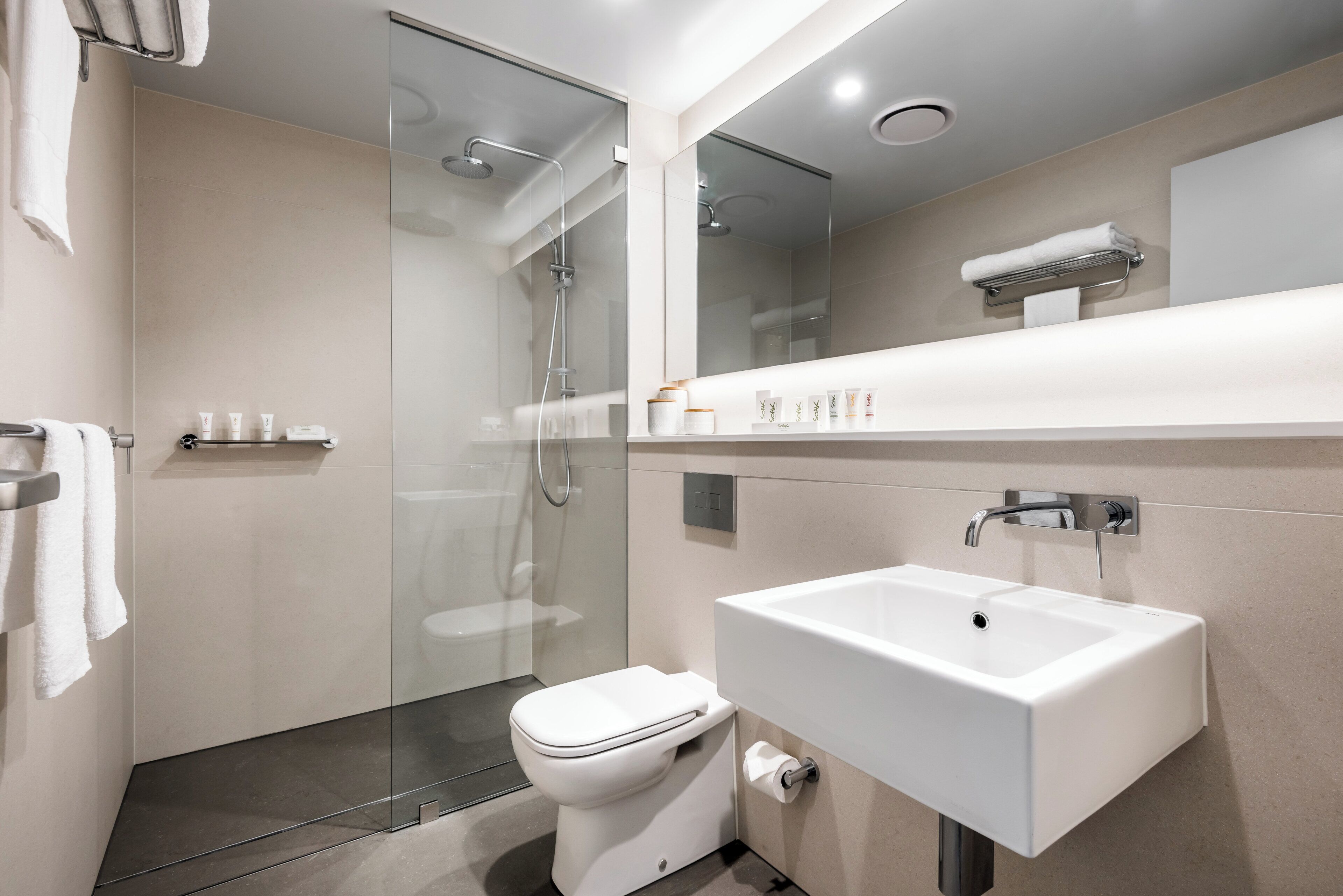A modern bathroom with a glass-enclosed shower, a white sink, and a toilet.