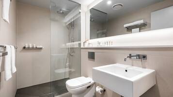 A modern bathroom with a glass-enclosed shower, a white sink, and a toilet.