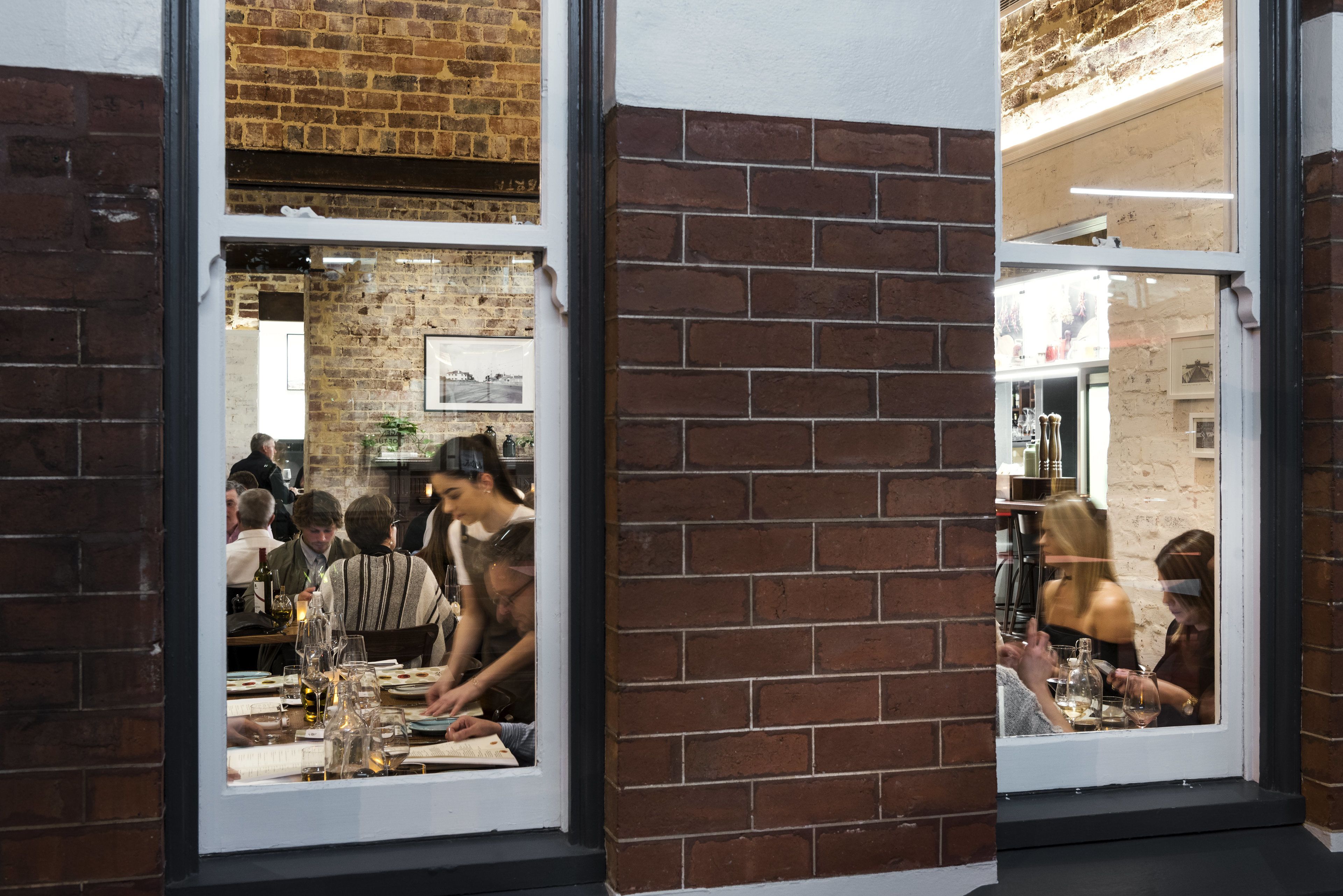 A restaurant with brick walls and large windows.