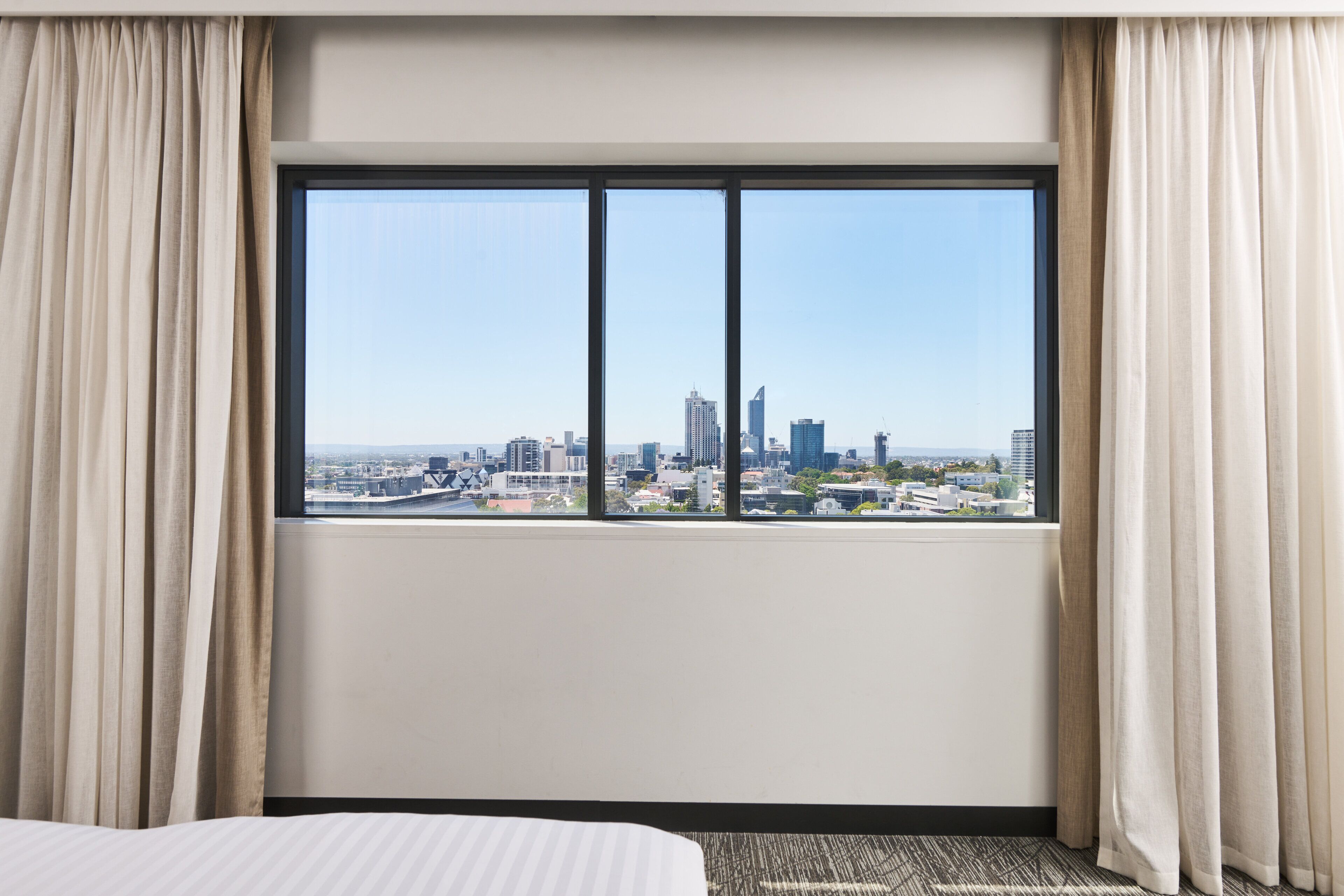 A hotel room with a large window offering a cityscape view.