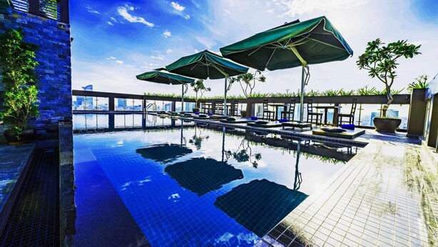 A rooftop infinity pool with lounge chairs and umbrellas, surrounded by stone walls and potted plants. - V Hotel Phnom Penh (Phnom Penh)
