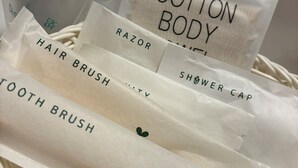 A basket containing various personal care items such as hairbrush, razor, and cotton body wash.