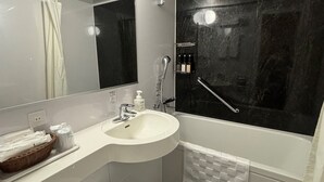 A modern bathroom with a white sink, a large mirror, a black marble shower wall, and a white towel rack.