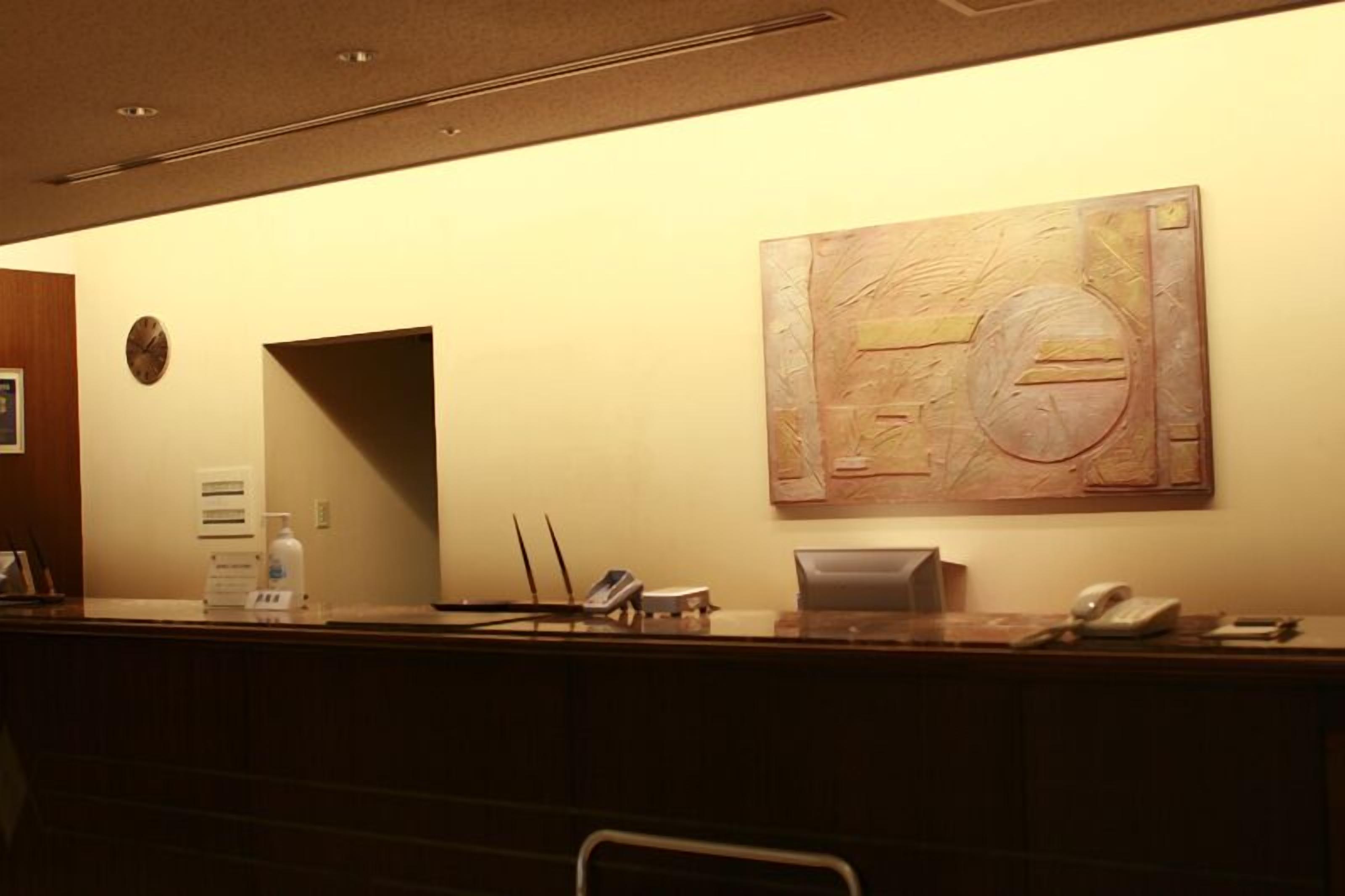 A reception desk with a clock, a bulletin board, and a large abstract painting on the wall.
