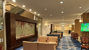 A hotel lobby with a patterned carpet, sofas, a television, and a large map on the wall.