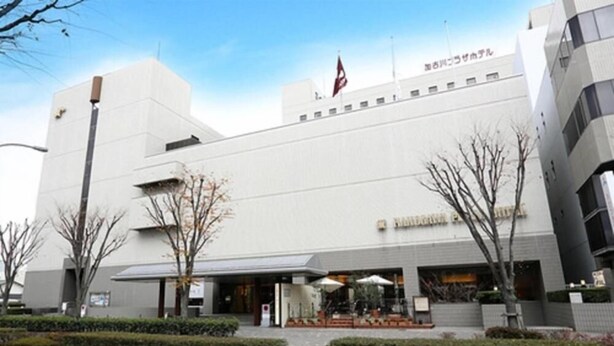 A modern building with a flat roof, a flag on top, and a sign with Japanese characters.
