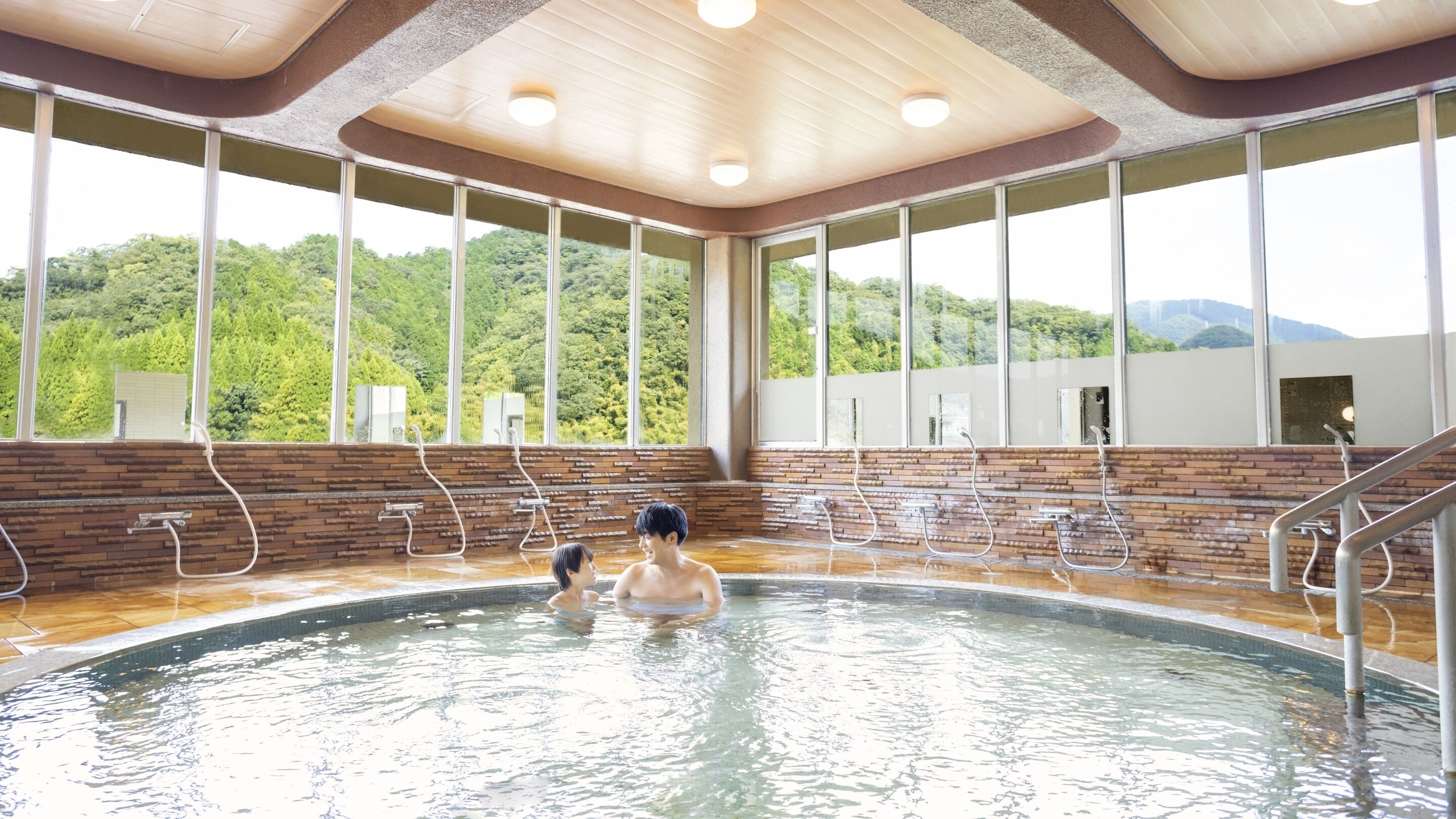 A hot tub with a wooden ceiling and large windows overlooking a forested area.