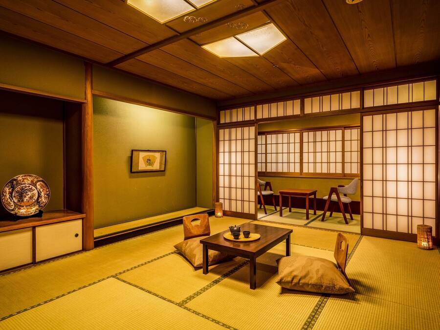 A traditional Japanese room with tatami flooring, a low table with cushions, and sliding shoji doors.