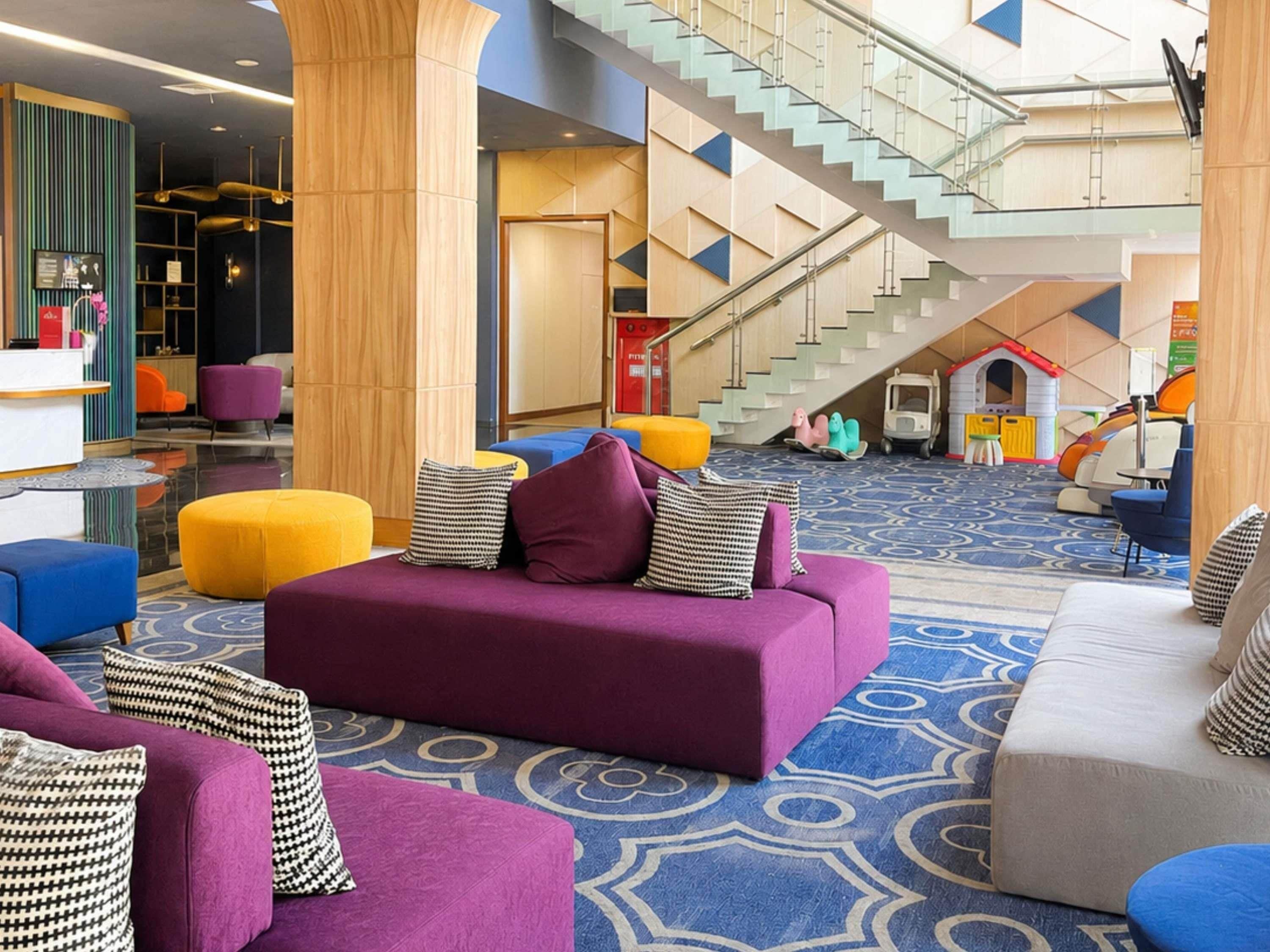 Un vestíbulo espacioso con un área de estar central, una escalera y una zona de juegos para niños.