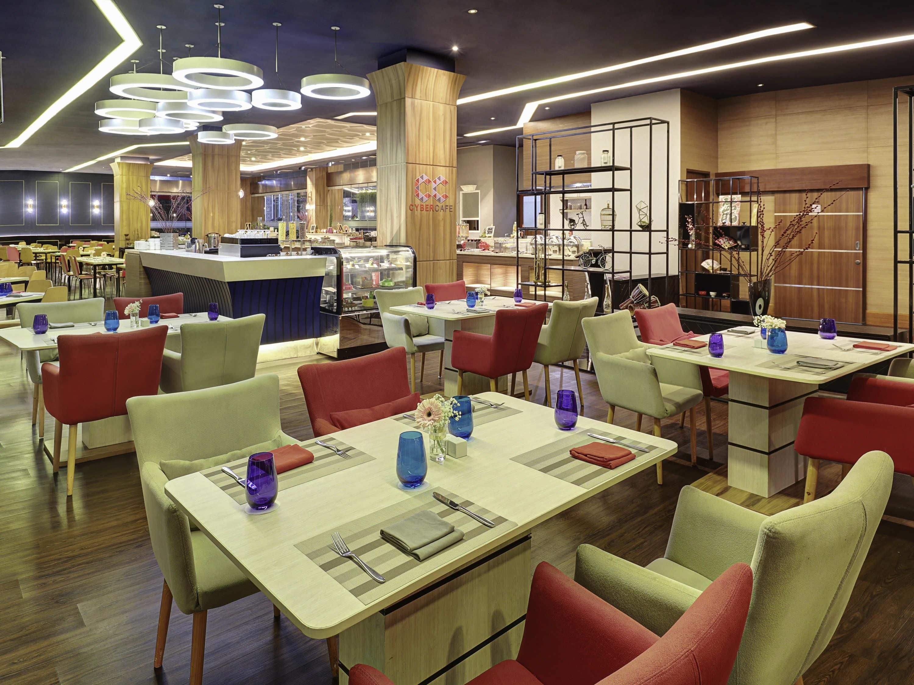 Ein modernes Restaurant mit mehreren Tischen, Stühlen und einer zentralen Theke mit einer Auslage.