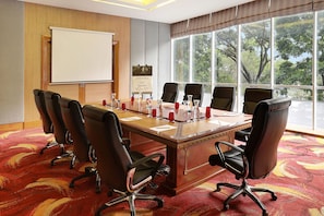 Un salón de conferencias con una mesa grande, seis sillas, una pizarra y un cartel en la pared.
