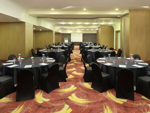 A conference room with round tables, black chairs, and a carpeted floor. - Mercure Bandung Nexa Supratman (Bandung)